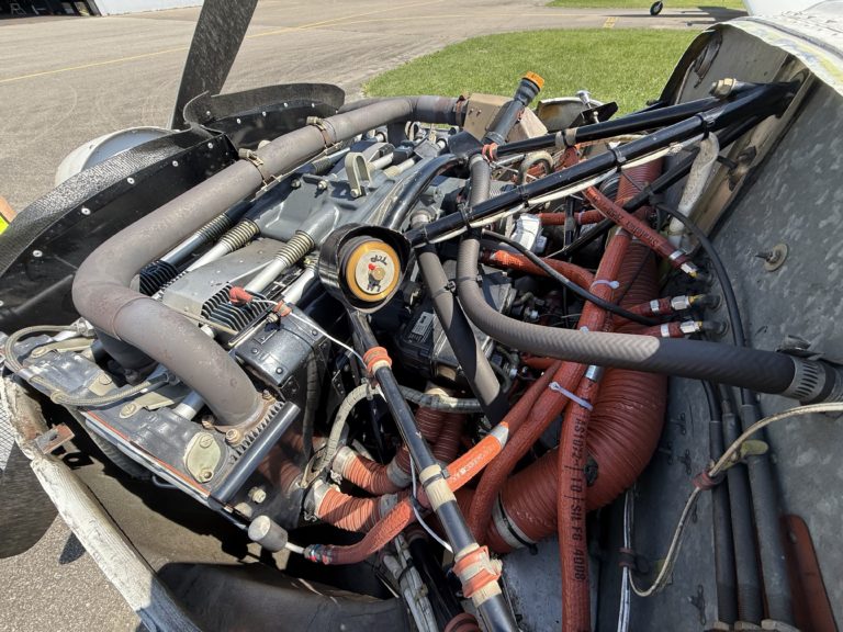 Exposed antique aircraft engine with hoses and pipes.