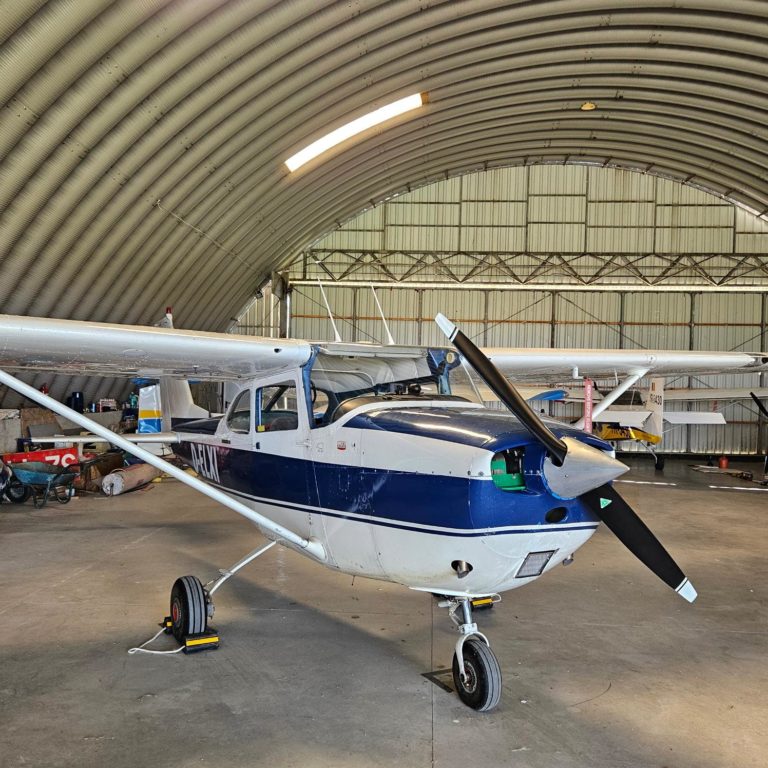 Small airplane parked inside large hangar.