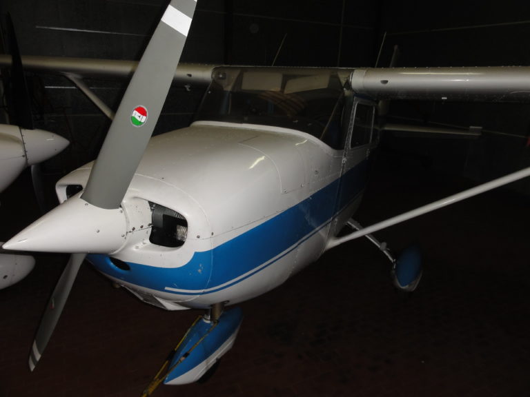 Small aircraft parked in a dimly lit hangar.