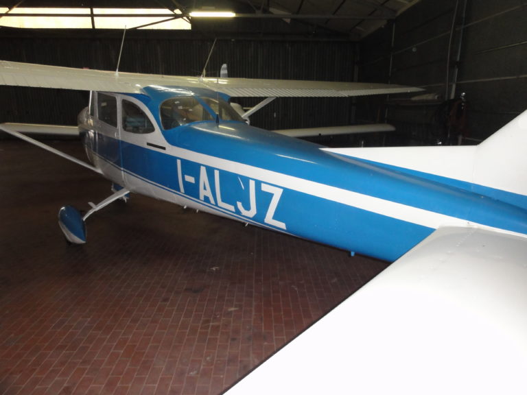 Blue and white airplane parked in hangar.