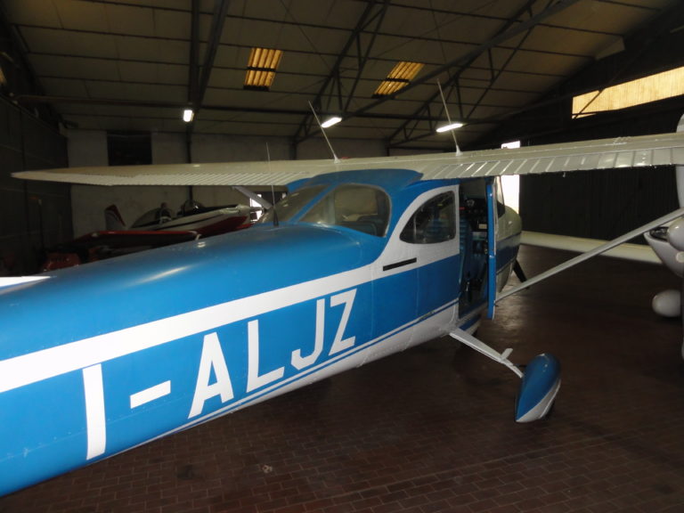 Blue and white light aircraft in hangar.