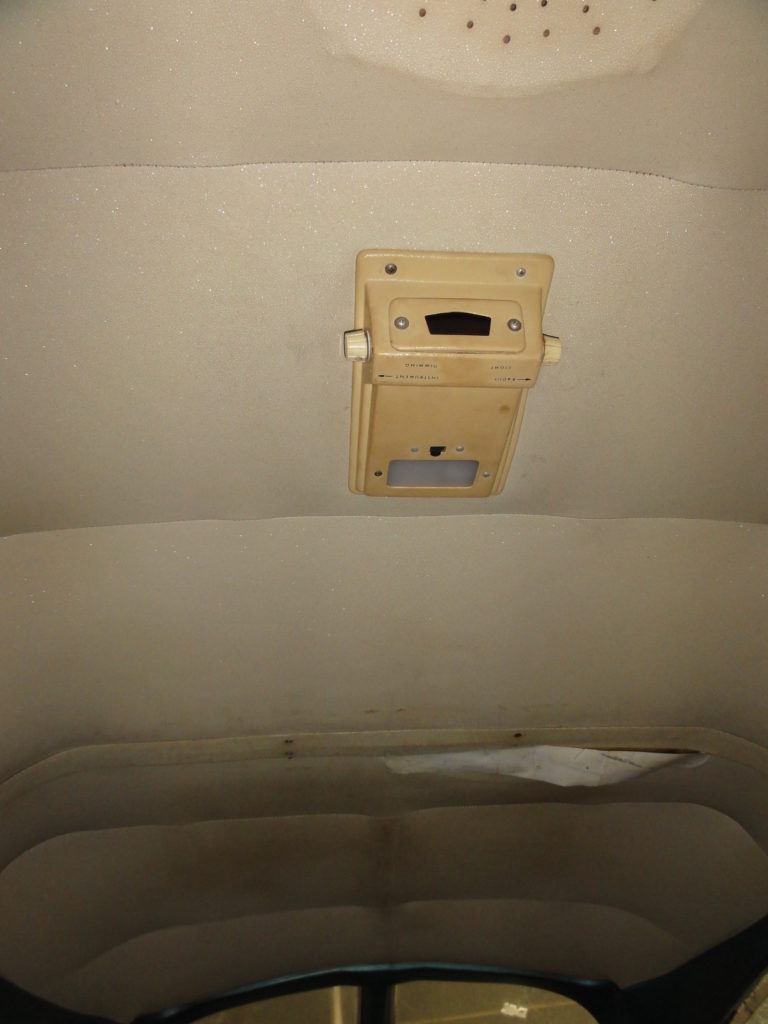 Vintage car interior dome light with tan headliner.