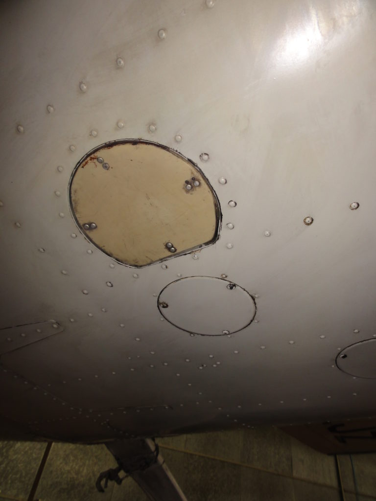 Underside of aircraft with metal panels and rivets.
