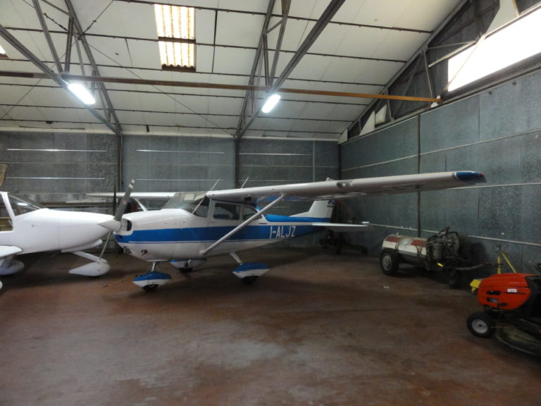 Small blue and white airplane in hangar.