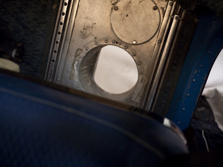 Partial view inside an aircraft cabin with window.