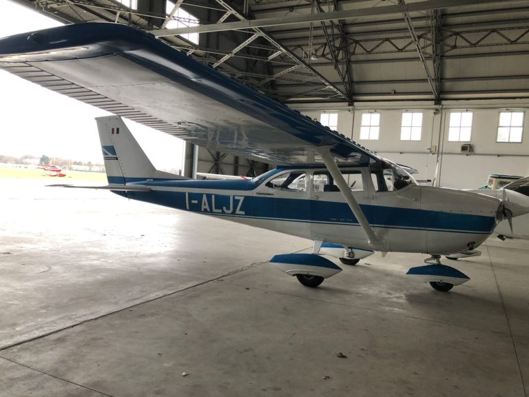 Small blue and white airplane in hangar