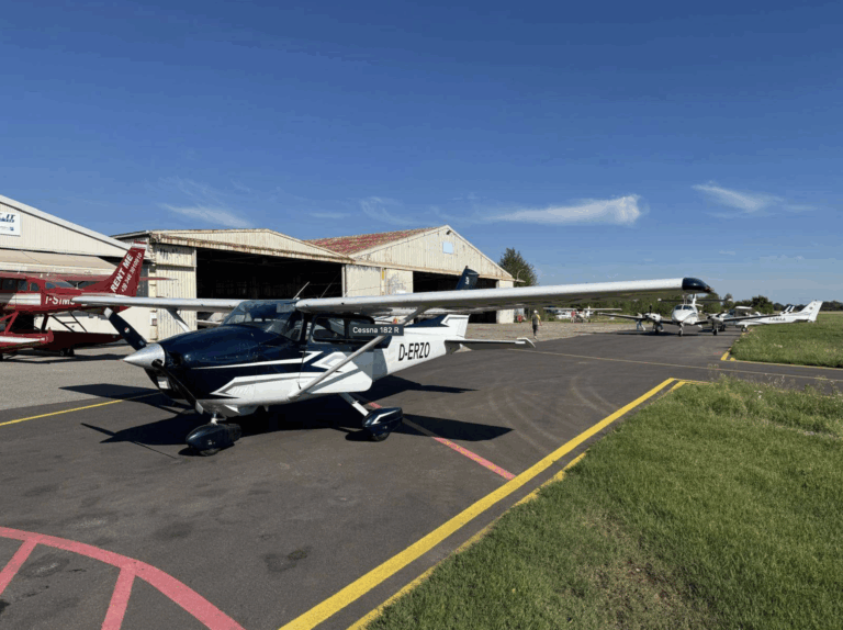Cessna airplane parked near hangar on sunny day.