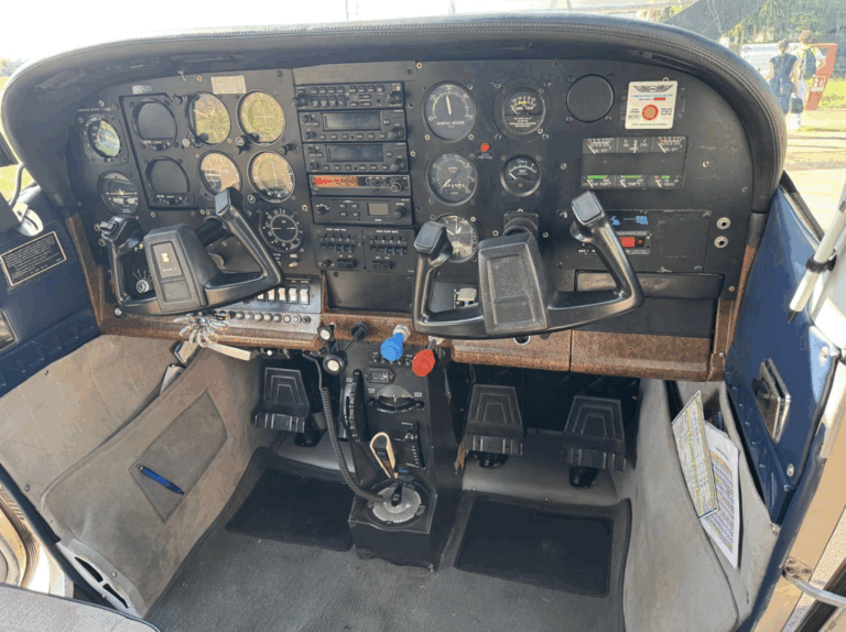 Small aircraft cockpit with controls and instruments.