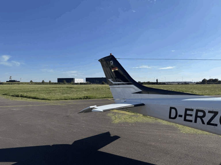 Airplane tail on runway, clear sky background.