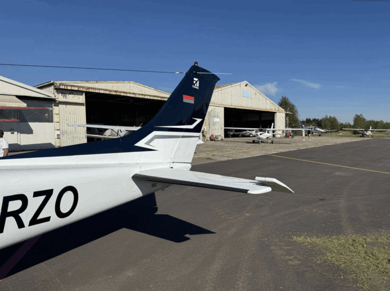 Airplane tail in front of hangar on sunny day.