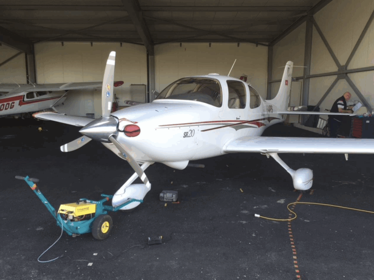 Small aircraft parked in a hangar with equipment.