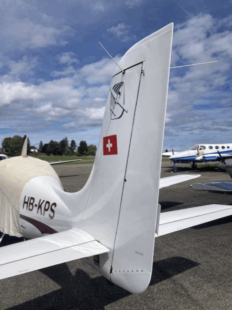 Swiss airplane tail fin on runway with blue sky.