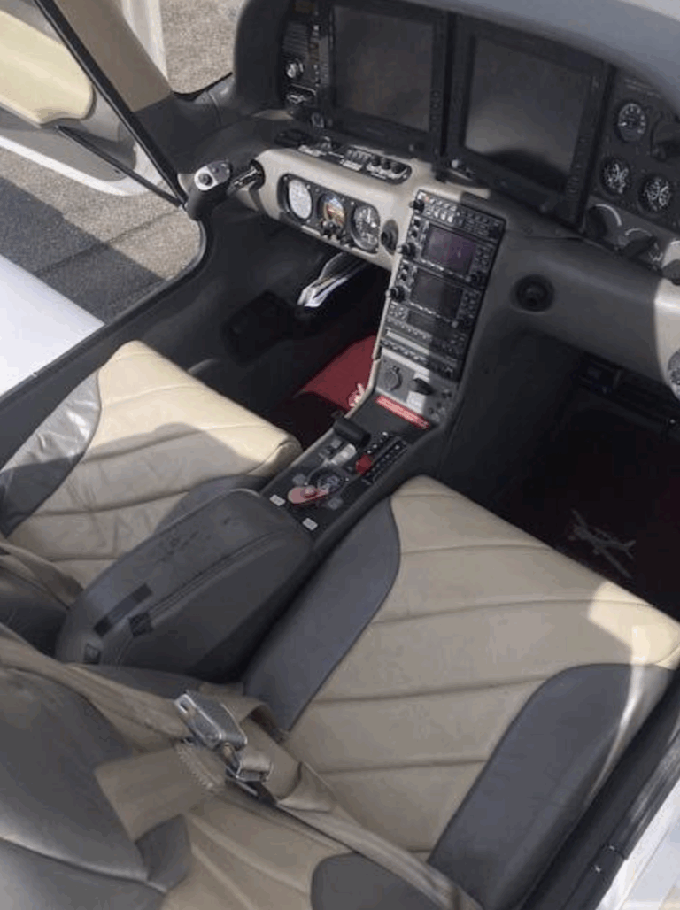Small airplane cockpit with beige seats and controls.