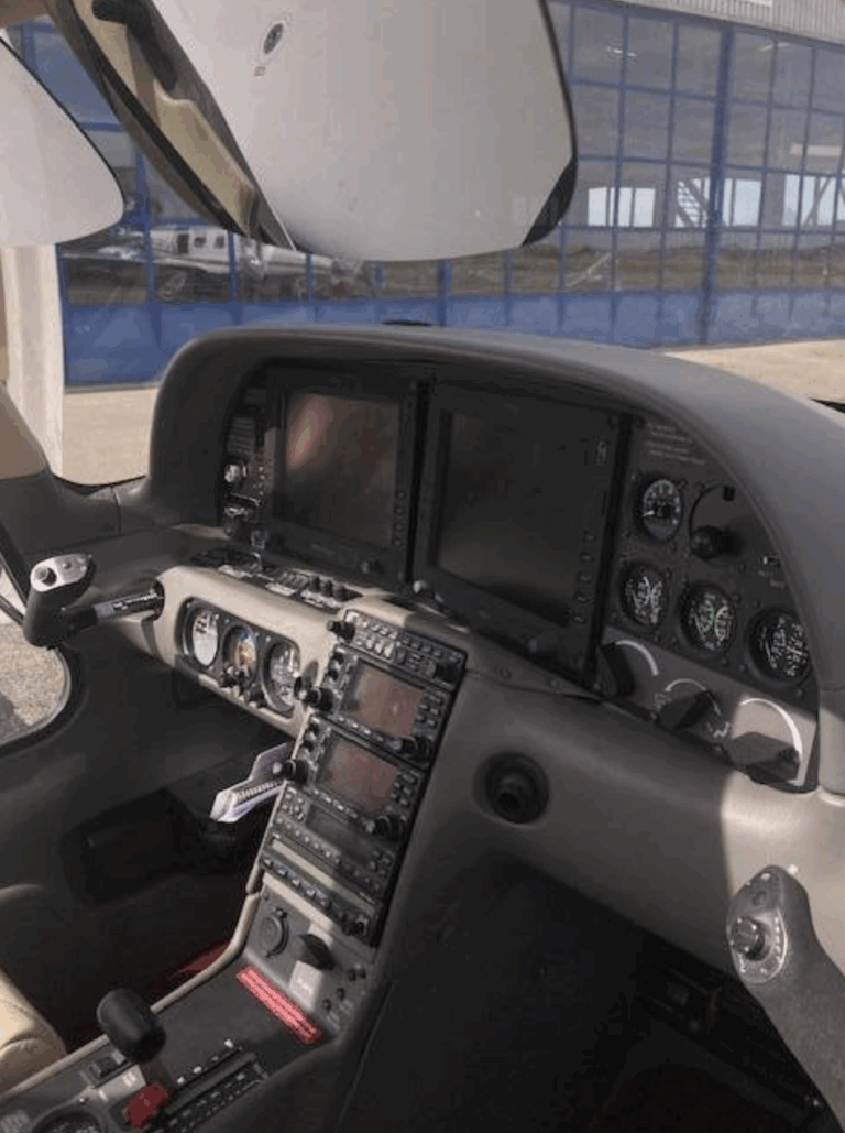 Small aircraft cockpit with flight instruments and controls.