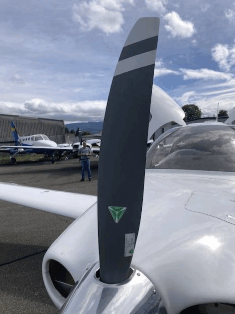Airplane propeller on tarmac with other planes.